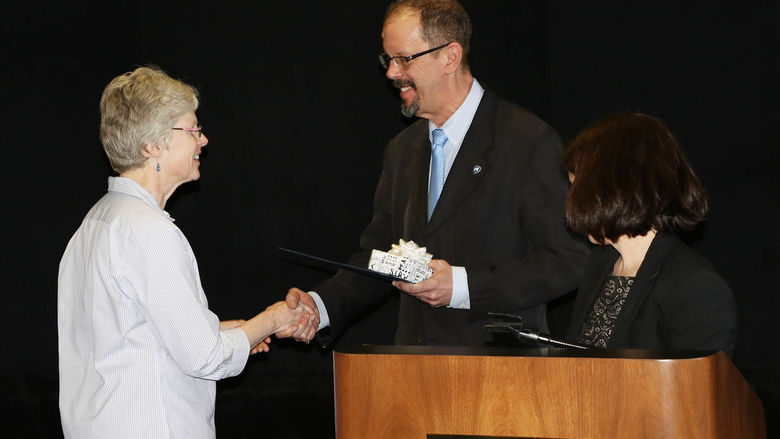 Chancellor Gary Lawler shakes Patricia Ferry's hand while congratulating her on 35 years of service to Penn State Hazleton. Director of Academic Affairs Elizabeth Wright is at right.