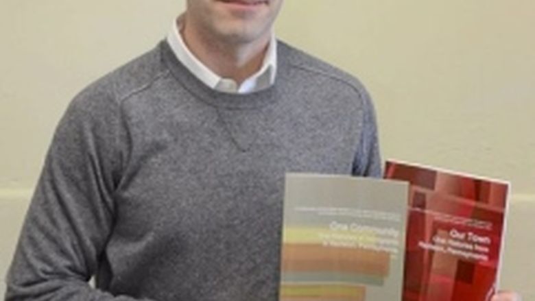 Professor Steven Accardi holding the two books his class published in the spring