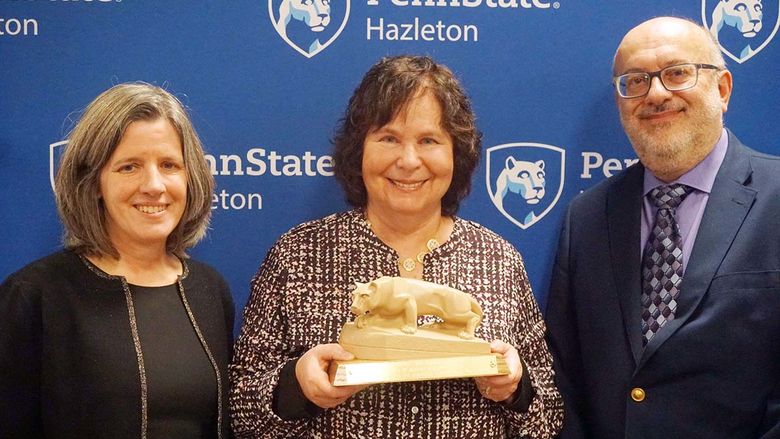 Woman in center holding Nittany Lion statue.