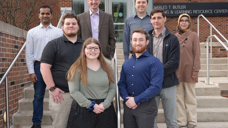 Group of students and professors standing outdoors on stairs.