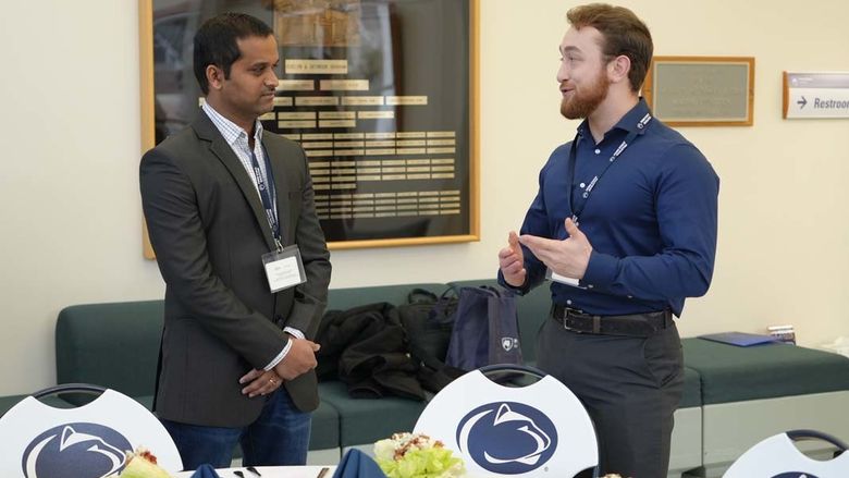 Two men speaking with one another next to a table.