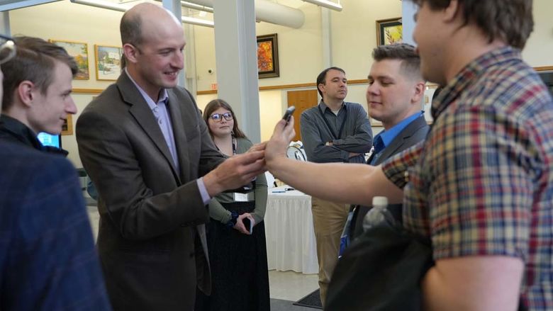 Man handing another man a cell phone.