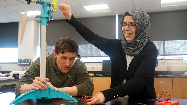 Instructor and student working with model wind turbine in a classroom.