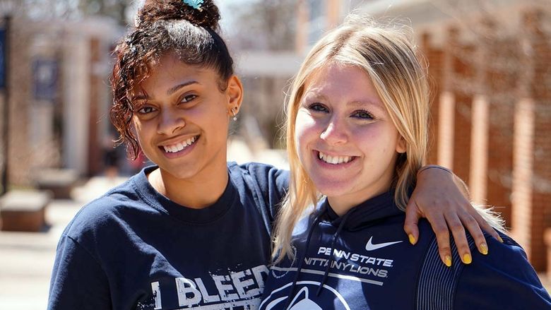 Two female students smiling on a college campus.