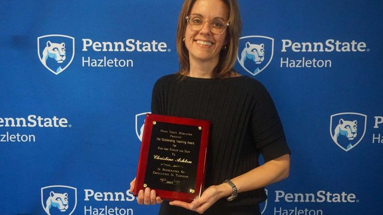 Woman smiling and holding plaque.