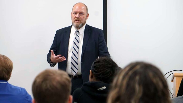 Man in a suit speaking to students in a classroom