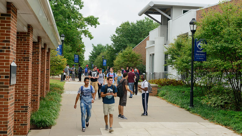 Students walking on a sidewalk at a college campus.