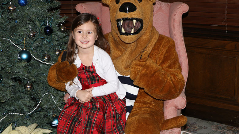 A child and the Nittany Lion pose near a Christmas tree.
