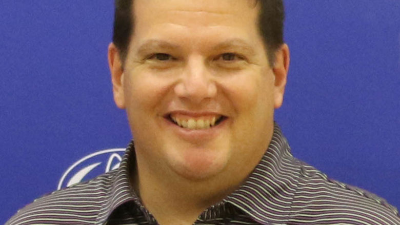 Man in striped polo shirt smiling.