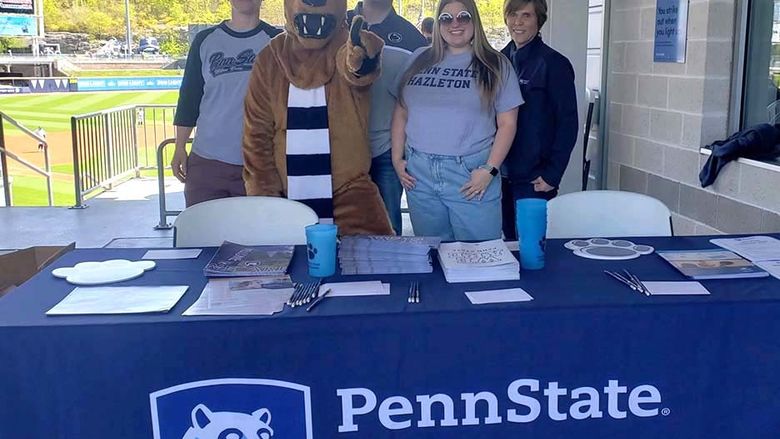 A group of people standing behind a table on a baseball stadium concourse.