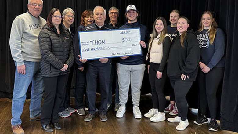 A group of people holding a large check and participating in a check presentation. 