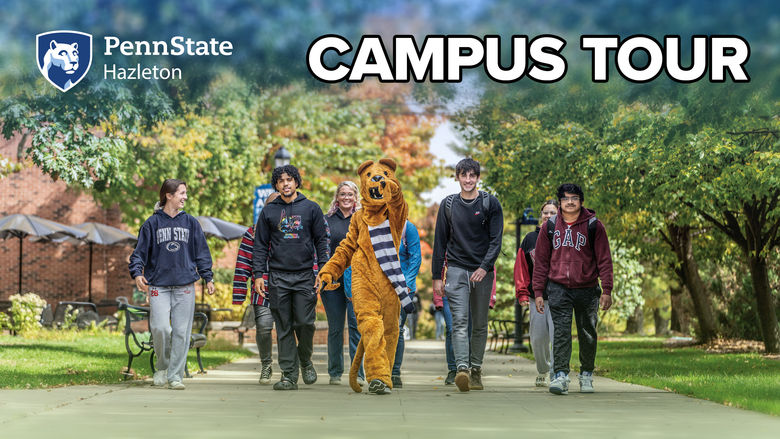 A group of students walking on the campus mall at Penn State Hazleton with the Nittany Lion mascot who is pointing. 