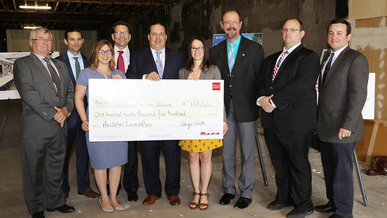 Group of business and community leaders standing and holding a large mock check.