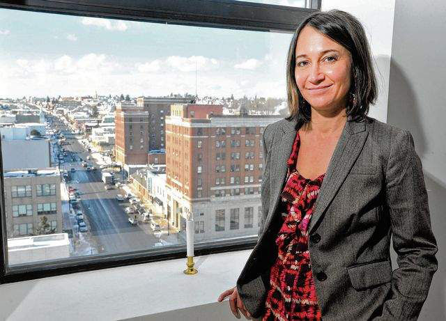 Woman standing next to window that shows city landscape.