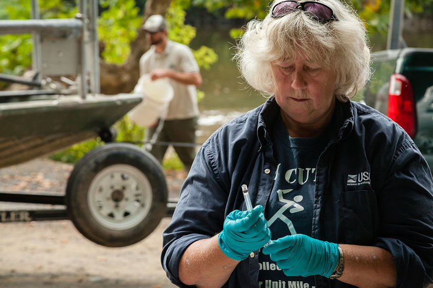 Female biologist with rubber gloves examining a sample.