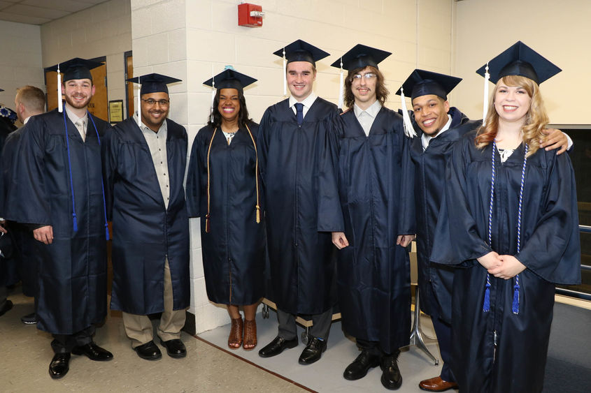 Seven smiling graduates in caps and gowns