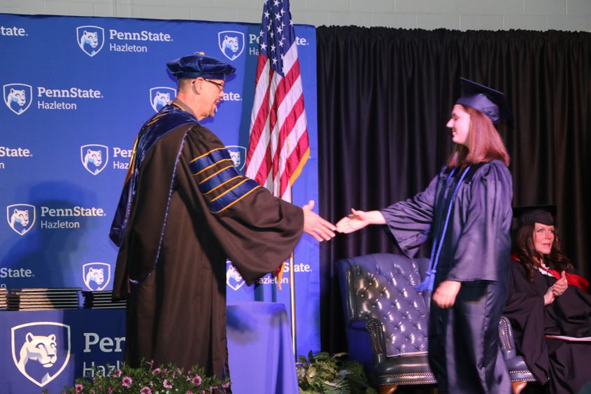 Graduate shakes hands with chancellor during commencement ceremony. 