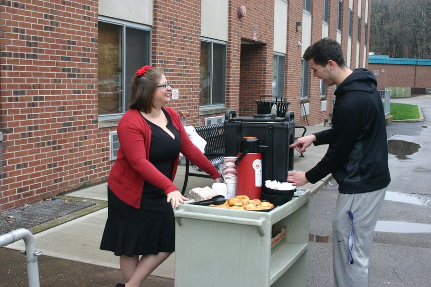 Associate Director of Student Services and Engagement Devon Purington serves coffee and danish to a student outside the residence halls at Penn State Hazleton.