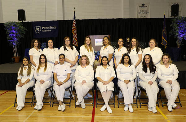 Group of 16 female graduates, seated and standing. 