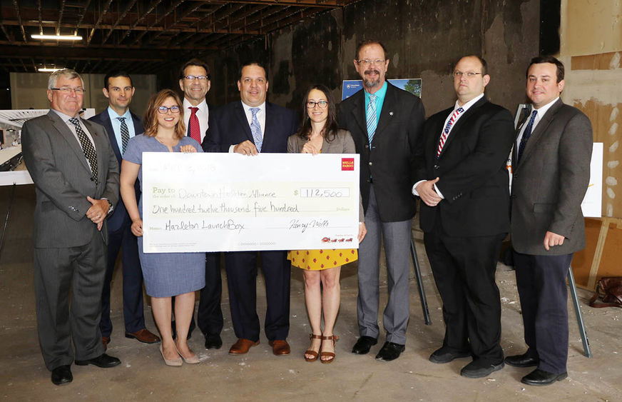 Nine smiling people standing with large check.