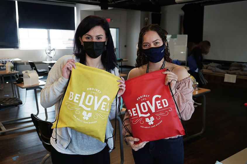 Students holding draw-string bags with "Beloved" written on them.