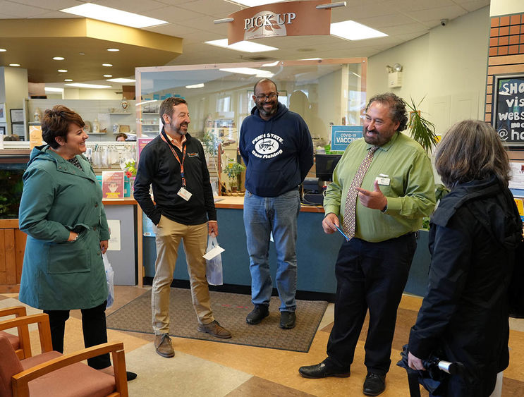 A group of people in the waiting area of a pharmacy talking and laughing.