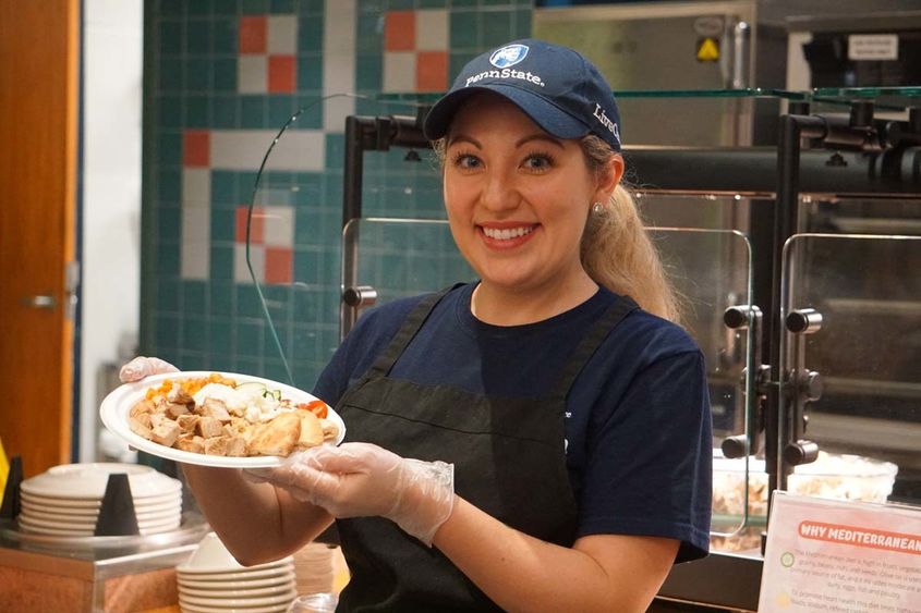 Female Housing and Food Services worker holding a plate of food.