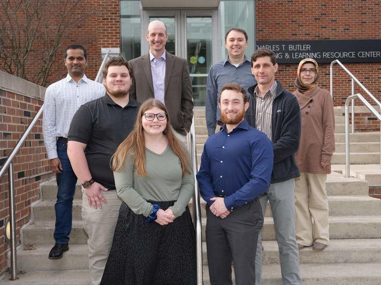 Group of students and professors standing outdoors on stairs.