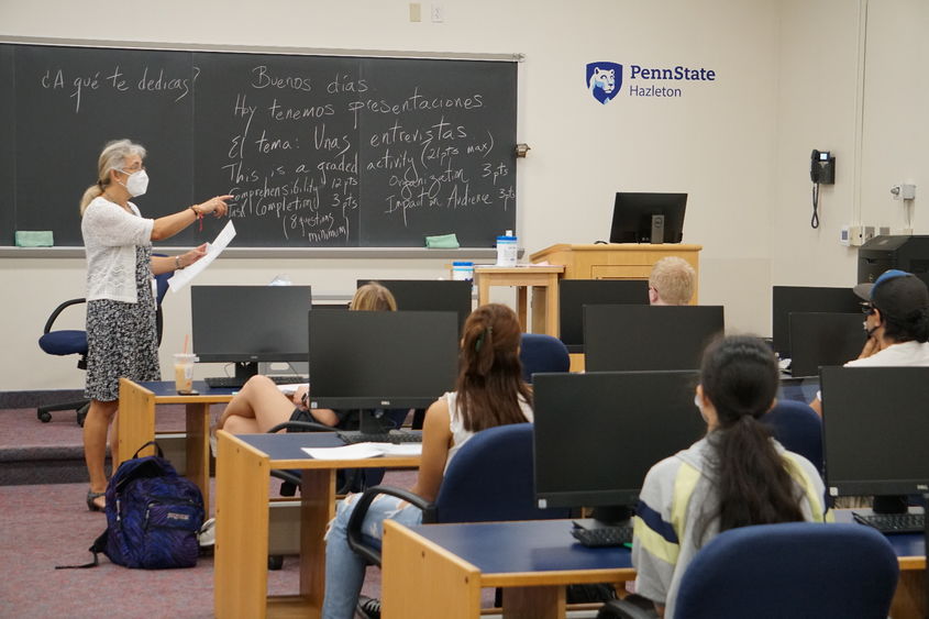 Teacher pointing to a student as others look on inside a classroom