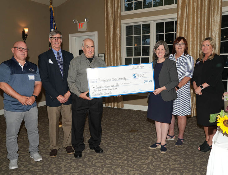 Six people standing together holding large check made out for $4,000.