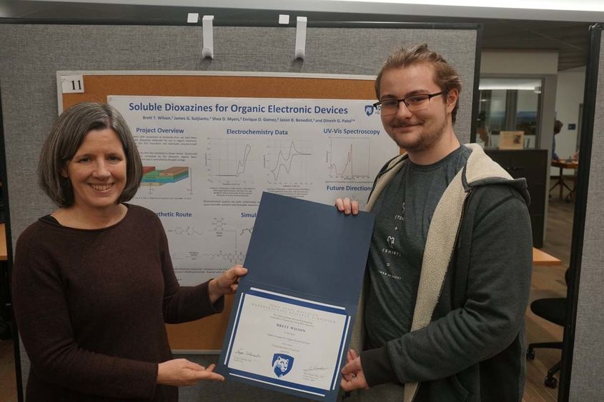 Male student holding certificate next to female administrator.