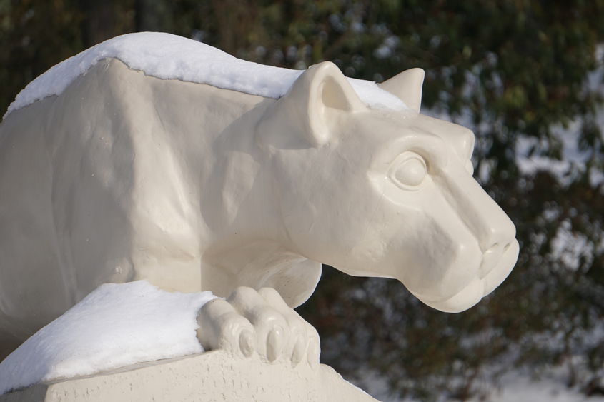 Statue of a lion looking out over snow.