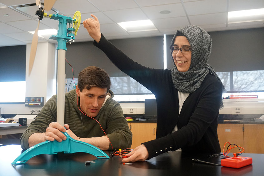 Instructor and student working with model wind turbine in a classroom.