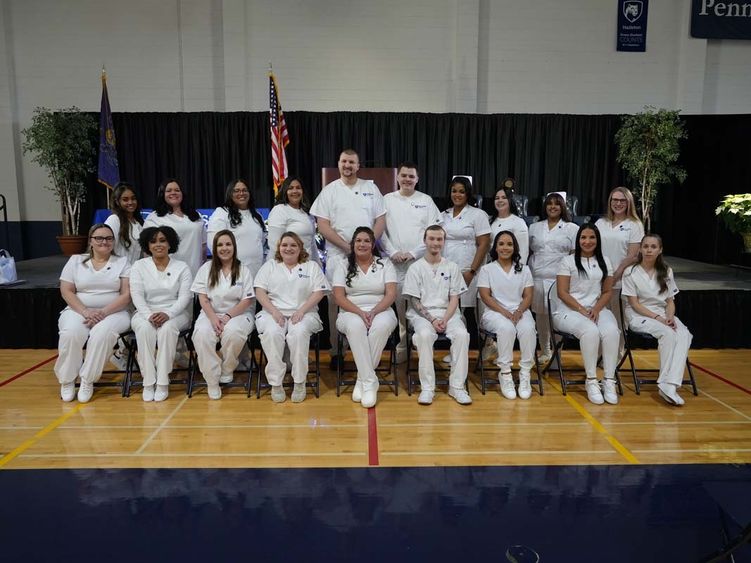Two rows of men and women in white nursing uniforms; one row standing and another seated