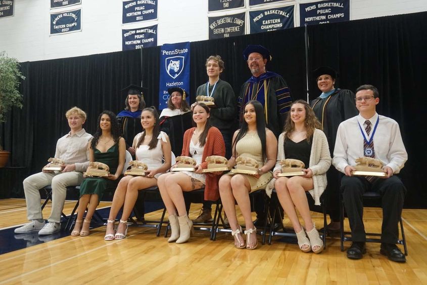 Students holding awards with faculty and staff seated with them.