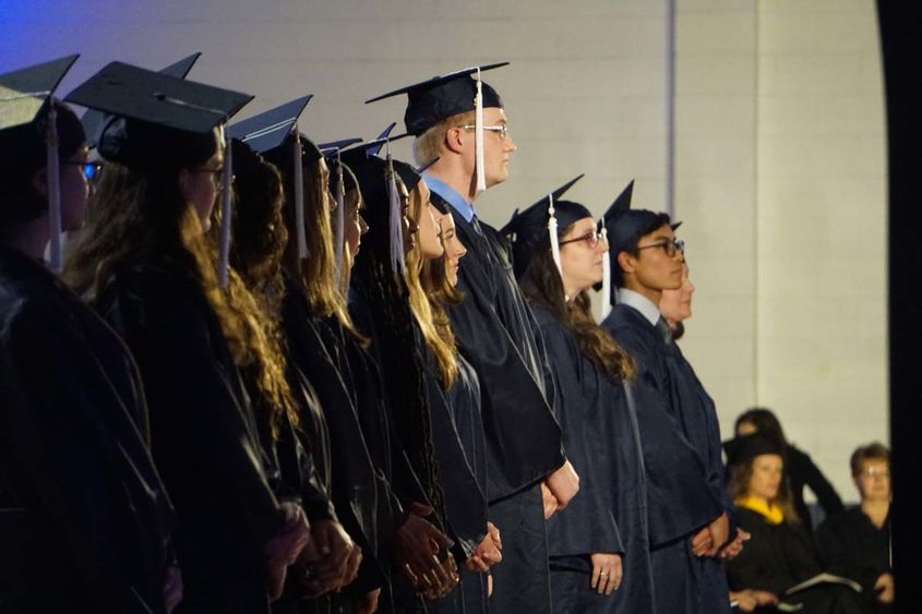 Students in graduation caps and gowns standing in a row