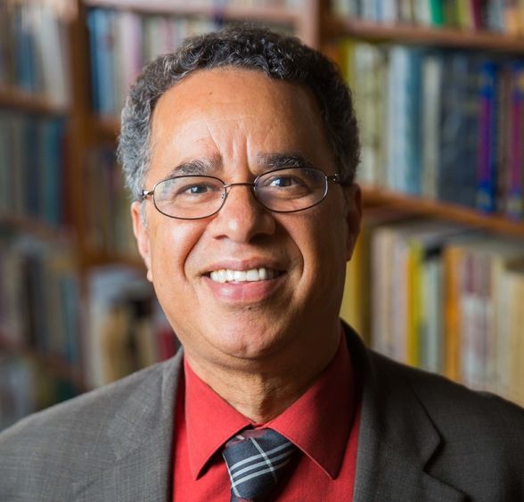 Man in glasses with a red shirt, tie, and suit jacket.