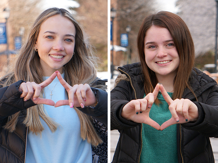 Two female students making diamond signs with their hands.