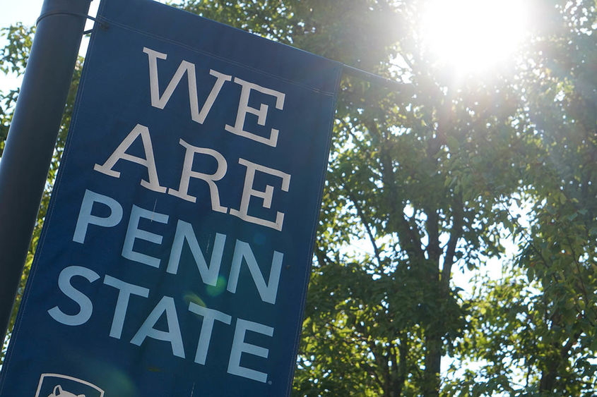 Blue 'We Are Penn State' banner with trees and sunshine in background