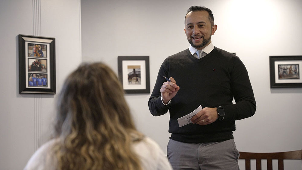 An admissions counselor standing with pen and paper in front of a student