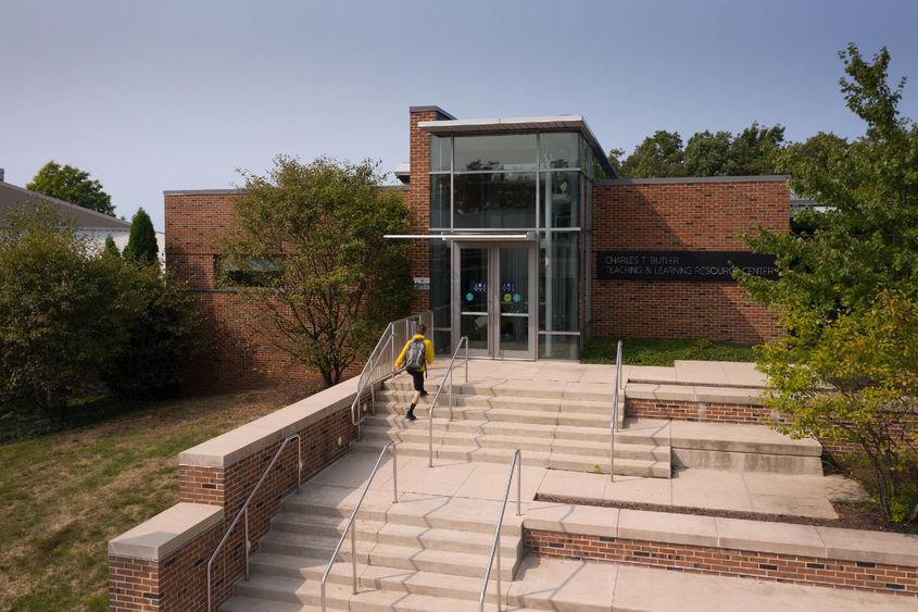 Student walking up stairs to brick building entrance at Penn State Hazleton.