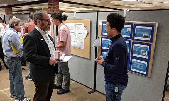 Alonzo Williams discusses his product with Michael Polgar, associate professor of sociology, during the annual research fair at Penn State Hazleton.