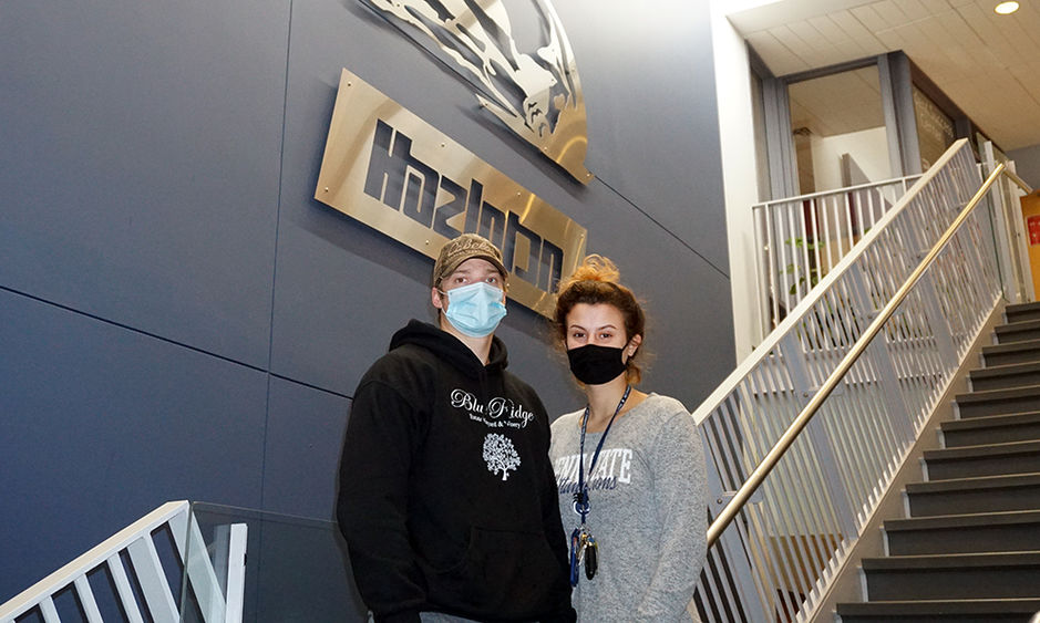 Female student and male student wearing masks and standing side by side on steps.