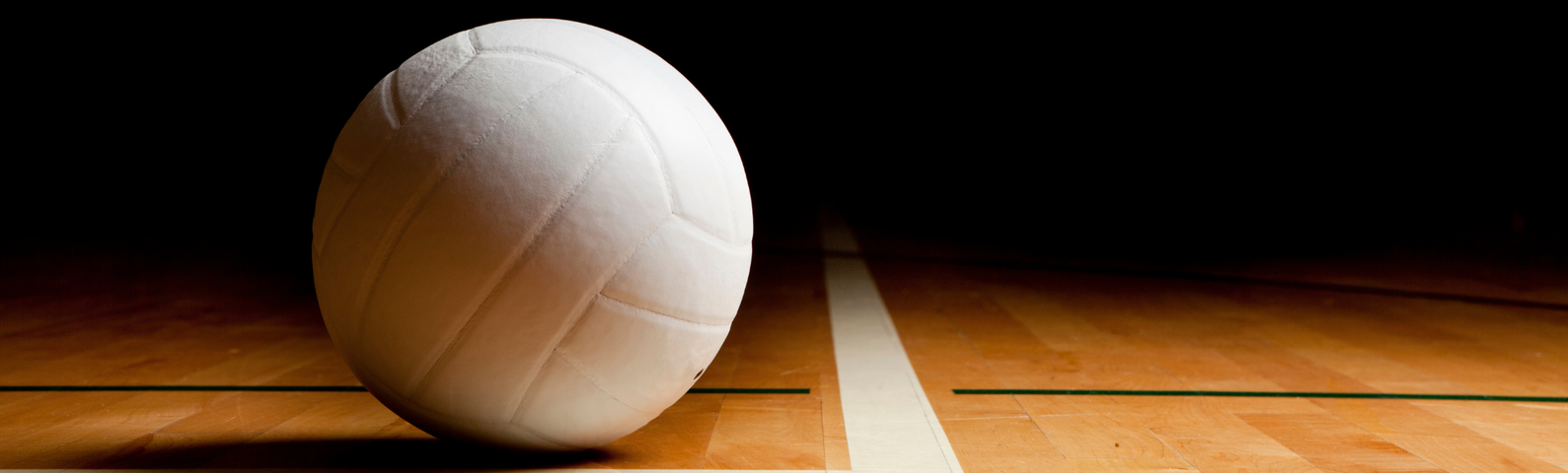 White volleyball on a dark hardwood court.
